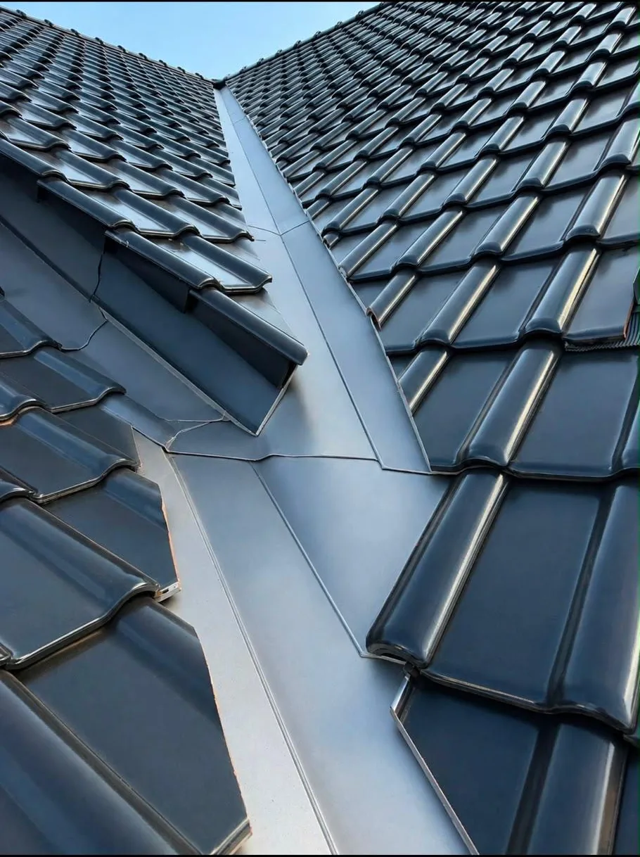 Sauber ausgeführte Metallkehle zwischen zwei dunkel eingedeckten Dachflächen