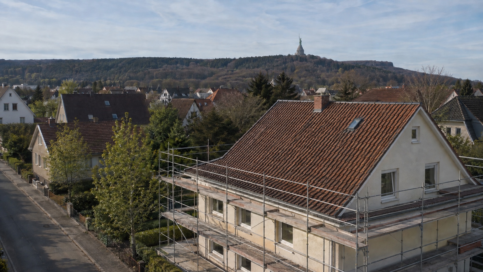 KI-generierte Illustration: eingerüstetes Ziegeldach mit Hermannsdenkmal im Hintergrund