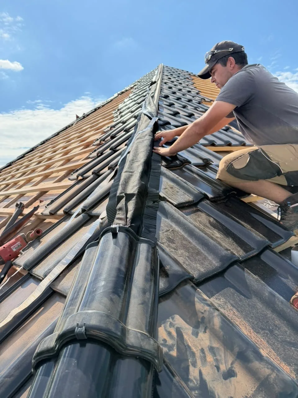 Dachdecker montiert Firstziegel auf einem neu eingedeckten Steildach