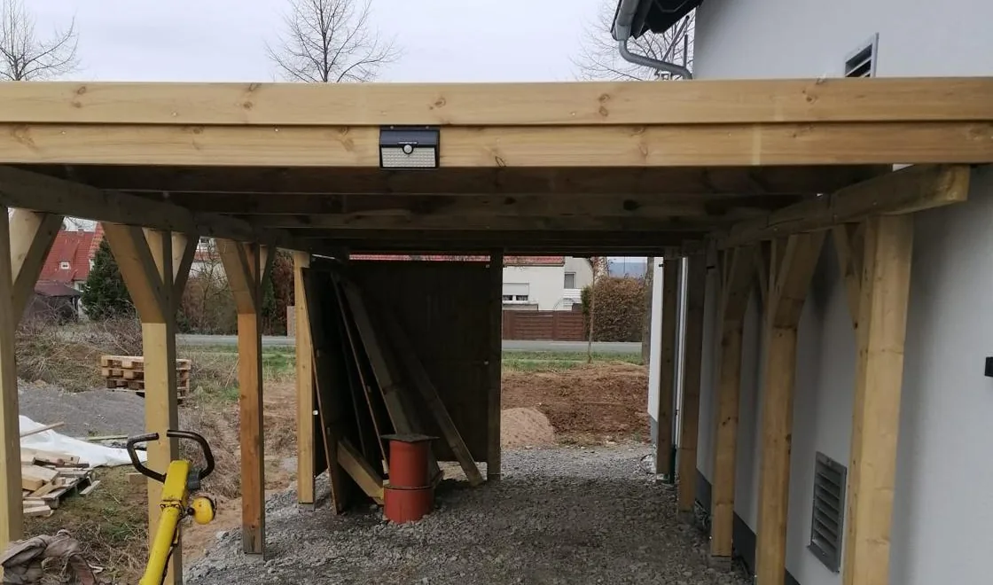 Neu errichtete Holzkonstruktion mit Stützen und Balken an einem Wohnhaus