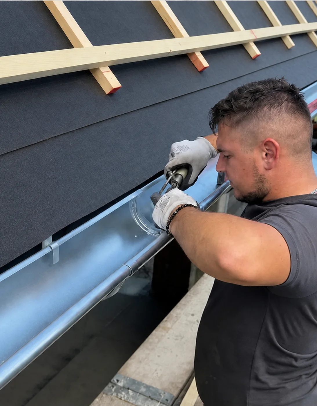 Dachdecker montiert eine Metallrinne am Dachrand